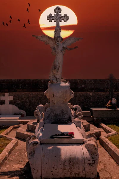 一个天使在坟墓上的形象和后面的太阳圆圈用红色照亮了整个场景 — 图库照片
