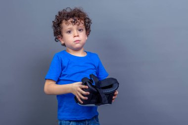 Çilli, kıvırcık saçlı ve elinde sanal gerçeklik gözlüğü olan bir çocuğun fotoğrafı.