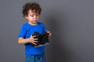 Sanal gerçeklik gözlüğü takan kıvırcık saçlı beyaz bir çocuğun fotoğrafı.