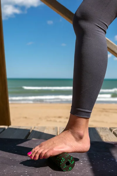 woman\'s foot using pilates foot roller by the sea