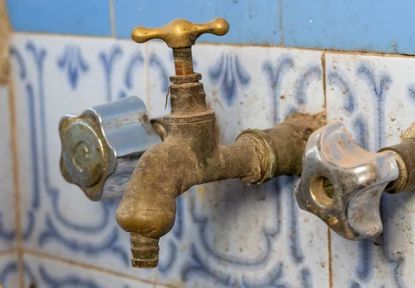 Döşeme duvarında eski paslı ve eski musluğun yakın çekimi