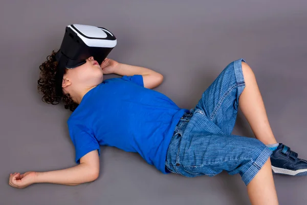 photo of child playing with virtual reality glasses. lying on the ground