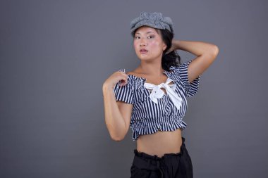 Gri arka planda kameraya poz veren genç Çinli kız.