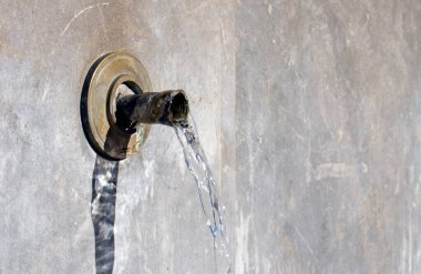 photo of rustic fountain with water spout coming out of the wall