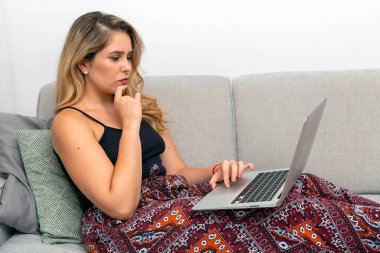 young woman sitting on sofa with laptop computer