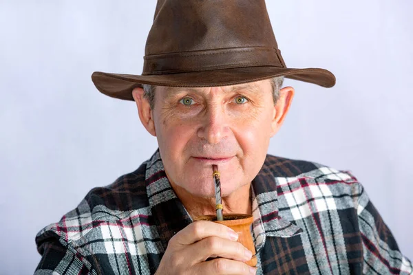 light-eyed older man drinking the typical infusion in Argentina called Mate