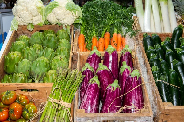 Marketteki tahta sandıkların içindeki sebzelerin fotoğrafı. Domates, karnabahar, salatalık, havuç, enginar, patlıcan vs..