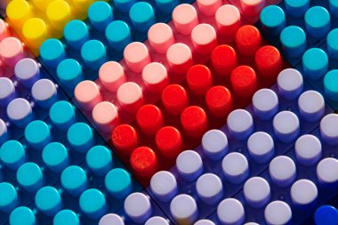 Çocuk oyun arka planı: Plastik çok renkli tuğlalar, bulanık, seçici odak düzlemi 