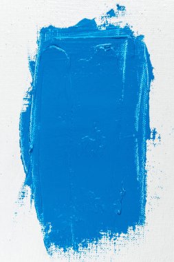 Beyaz, sanatsal bir gazlı bez üzerinde geniş bir mavi boya darbesi yakın çekim, tonlama, serbest alan 