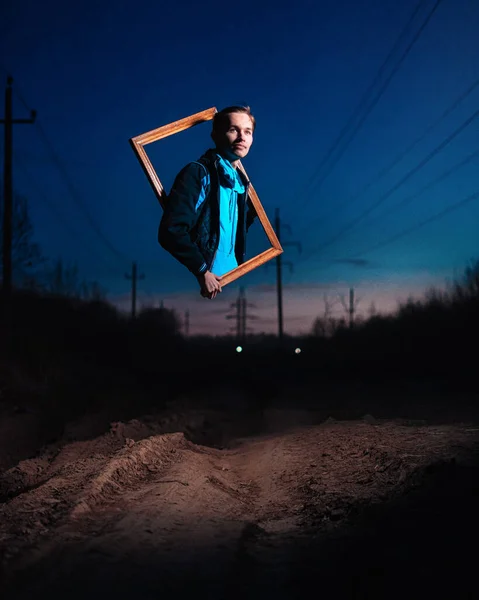 Un type sort d'un cadre suspendu dans les airs la nuit sur un chemin de terre vide. — Photo
