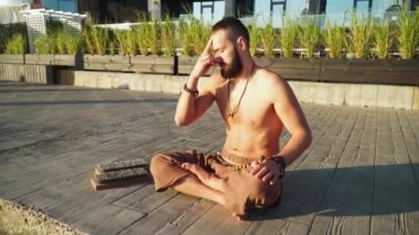 Sakallı adam gün doğumunda yoga yapıyor. 