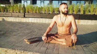 Sakallı adam gün doğumunda yoga yapıyor. 