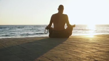 Sakallı adam gün doğumunda yoga yapıyor. 