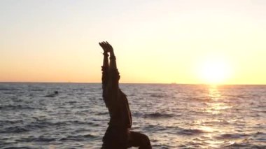 Sakallı adam gün doğumunda yoga yapıyor. 