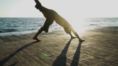 Sakallı adam gün doğumunda yoga yapıyor. 
