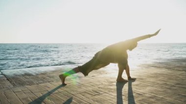 Sakallı adam gün doğumunda yoga yapıyor. 