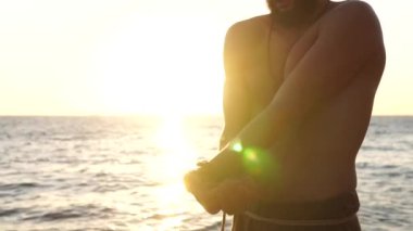 Sakallı adam gün doğumunda yoga yapıyor. 