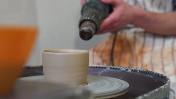 Potter torkar en hantverk kopp med en const ruction hårtork — Stockvideo