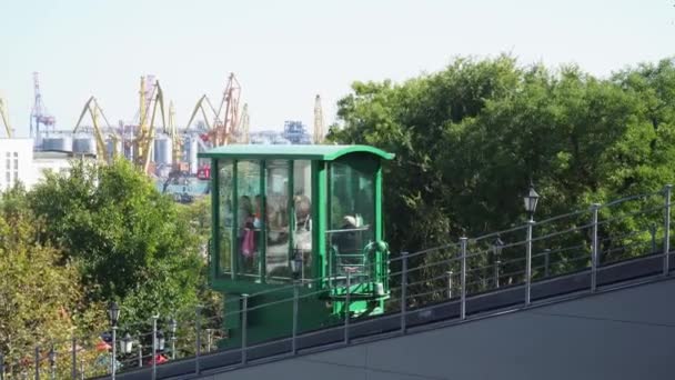 Zielona kolejka linowa wznosi się wraz z ludźmi na tle portu — Wideo stockowe