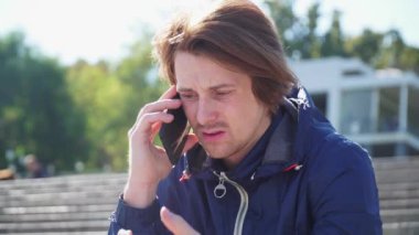 Adam basamaklarda oturuyor ve telefonda mavi ceketle duygusal iletişim kuruyor.