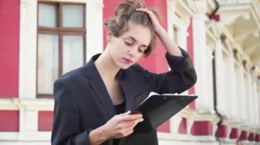 Siyah ceketli esmer kız kırmızı bir evin belgeleriyle oturuyor.