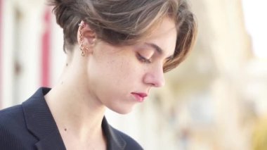 Esmer, siyah ceketli, rüzgarda yanıp sönüyor ve saçını düzleştiriyor.