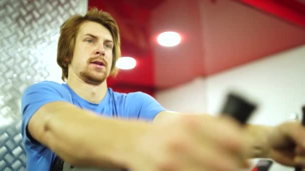 Rödhårig kille tränade träningsapparaten i det röda gymmet.närbild — Stockvideo