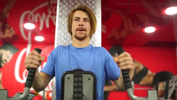 Red-haired guy worked out on the training apparatus in the red gym.close-up — Stock Video