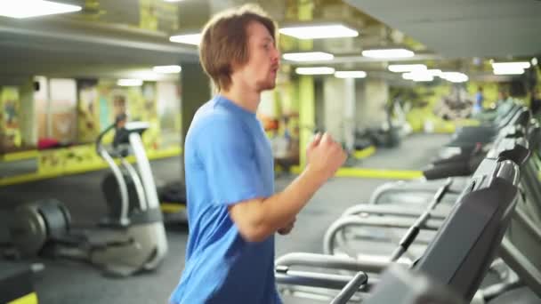 Zblízka běží zrzka chlap v modré t-shirt.treadmill v tělocvičně — Stock video