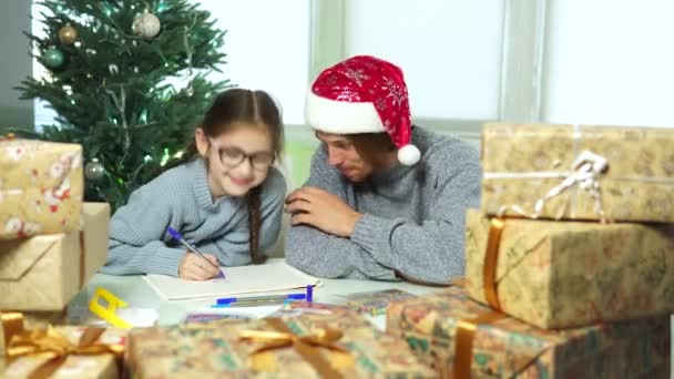Tata i córka na Boże Narodzenie.girl rysuje z mężczyzną w kapeluszu Mikołaja — Wideo stockowe