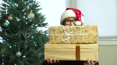 Noel Baba şapkalı komik kız elinde hediyelerle büyük kutular tutuyor.