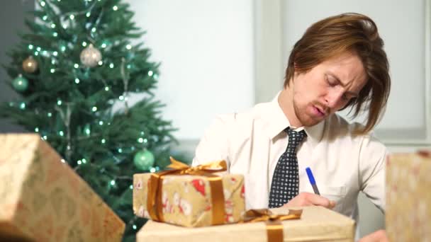 Офисный работник подписывает новогодние подарки. Бизнесмен с Рождеством Христовым — стоковое видео