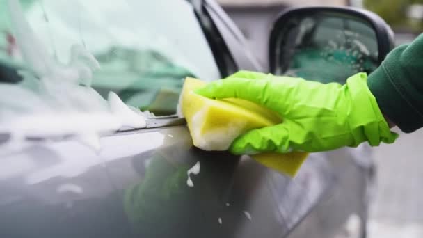 Lave-auto essuie une voiture grise avec un mouvement de mousse sponge.camera — Video