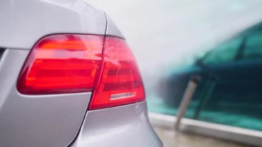 Gri bir arabayı kapat. Arabanın farını yüksek basınçlı suyla yıka.