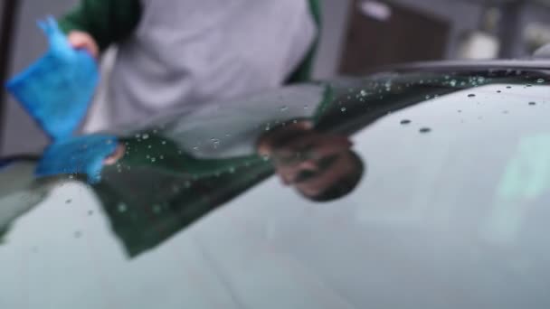 Primo piano di auto bagnata glass.man pulisce un finestrino con uno straccio blu — Video Stock