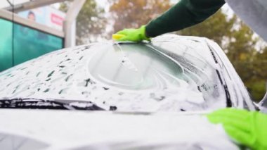 Araba yıkama makinesi sokakta gri BMW araba yıkıyor.