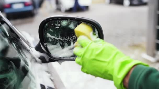 Mann in grünen Handschuhen wäscht Rückspiegel mit gelbem Schaumschwamm — Stockvideo
