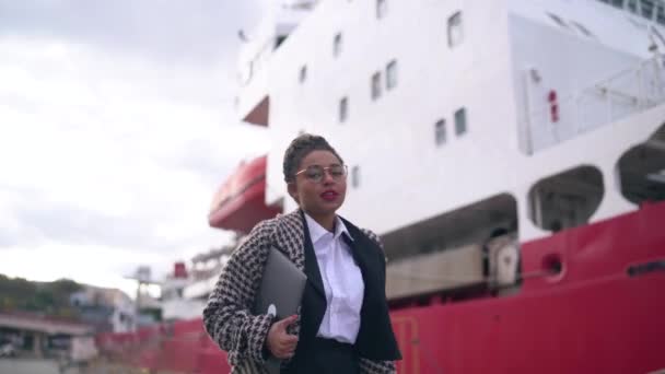 Donker gevilde vrouw in bril loopt met een groot schip op de achtergrond — Stockvideo