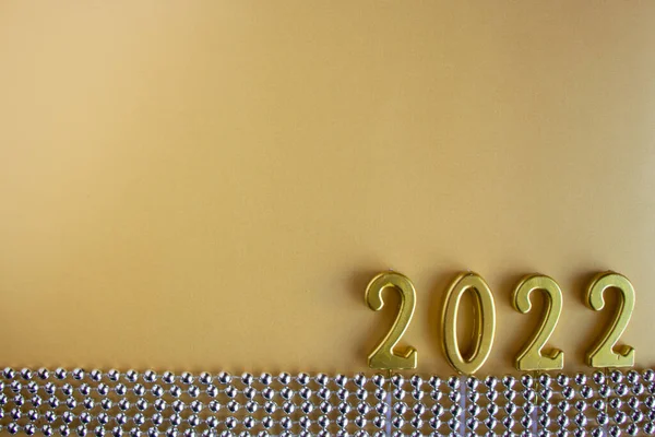 2022 Yeni Yıl sayısı, gümüş Noel boncuklarının yanında sarı bir zemin üzerinde ahşap numaralar halinde serilmiştir.