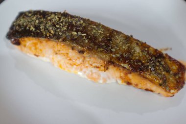 Beyaz tabakta ızgara somon bifteği.