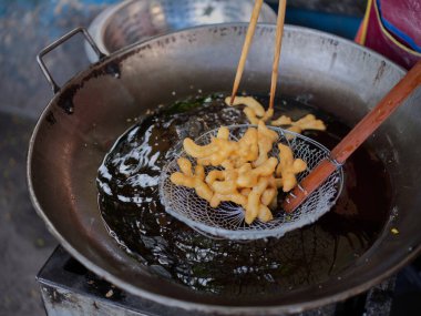 Die cut of Deep fried Chinese Doughnut in an big oil pan