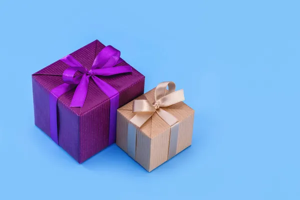 Two boxes with gifts in an elegant package with ribbons and bows. Blue background, copy space.