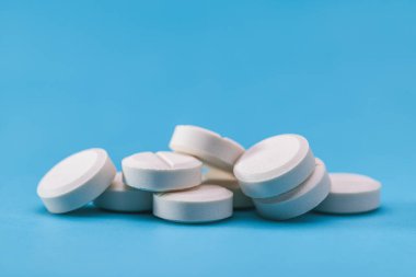 Mavi arka planda beyaz haplar, kopyalama alanı. Eczane, eczacılık..