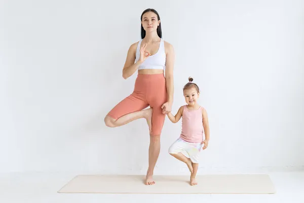 Junge Frau Praktiziert Yoga Mit Ihrer Tochter Kinderyoga Vrikshasana Pose — Stockfoto