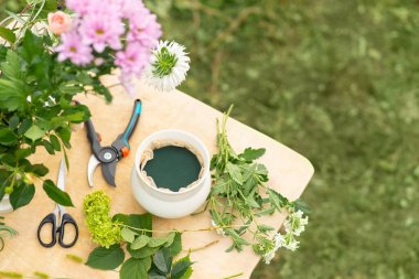 Çiçek saksısındaki köpüğün yakın plan resmi. Bir masada, fotokopi alanı olan doğal yeşil bir arka plan var. Buketler ve çiçekler yaratmak için araç.