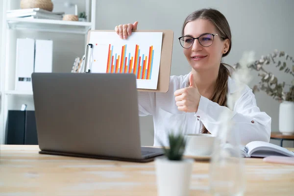 Giovane Donna Tiene Grafici Aziendali Negli Appunti Fronte Computer Portatile — Foto Stock