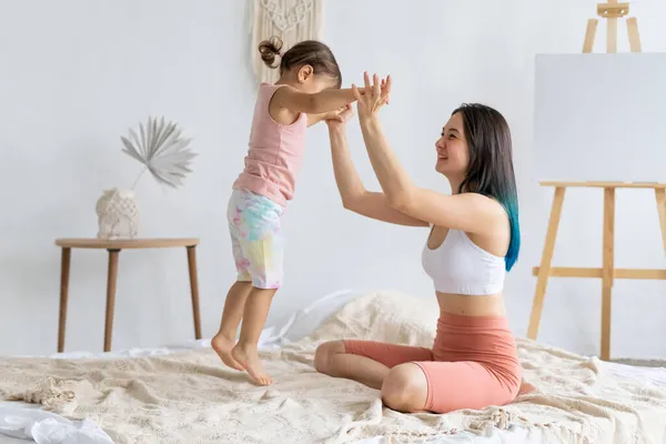 Mãe Alegre Segura Sua Filha Pulando Mão Cama Vida Familiar — Fotografia de Stock