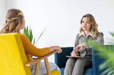 Psikolog ergen hastasıyla seans yapıyor. Kopyalama alanı olan ofis arkaplanı.