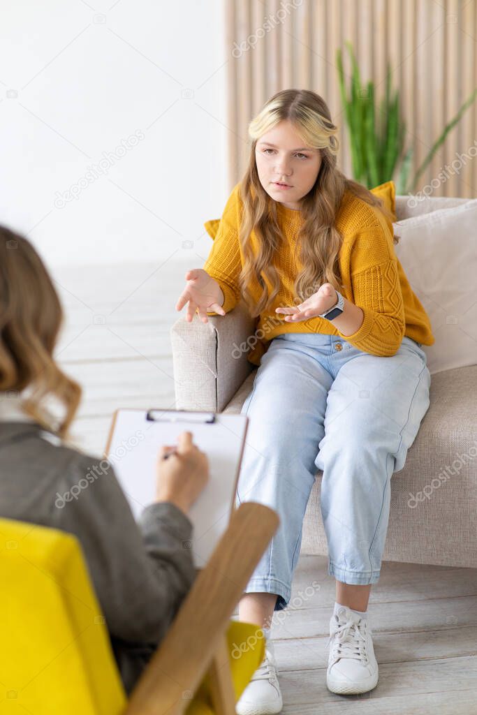 Patient teenager girl on consultation with psychologist. Blurred foreground.