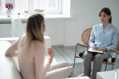 Genç kadın psikolog resepsiyonu aydınlık odada yönetiyor..